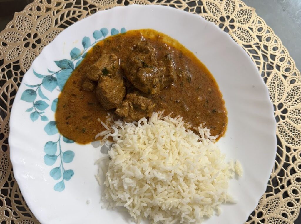 Chicken curry served beside a portion of plain boiled rice