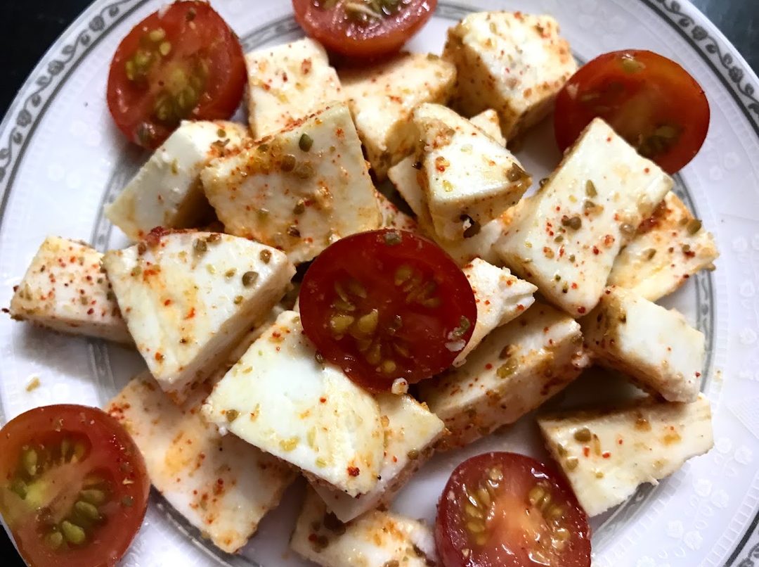 Paneer cubes with cherry tomatoes and chilli flakes